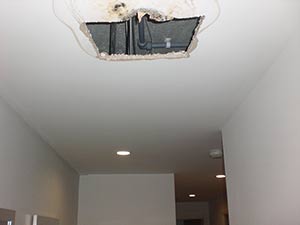 Hole in hallway ceiling following water damage requires plaster repair in Southfields SW18, SW19